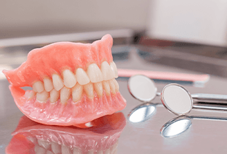 Two dentures set on a glass countertop