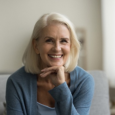 Senior woman sitting forward on couch and smiling