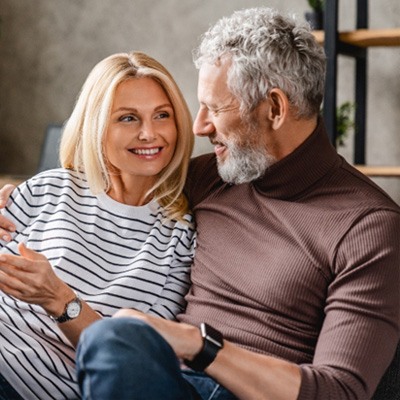 Couple smiling on couch after seeing a Delta Dental Premier dentist in San Marcos 