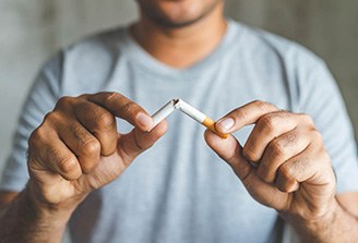 hands breaking a cigarette in half