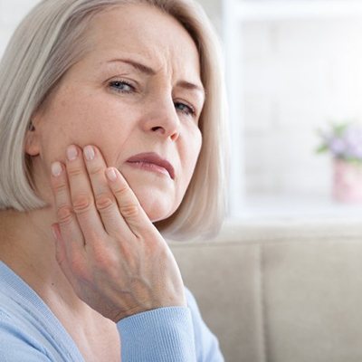 a woman touching her jaw due to tooth pain