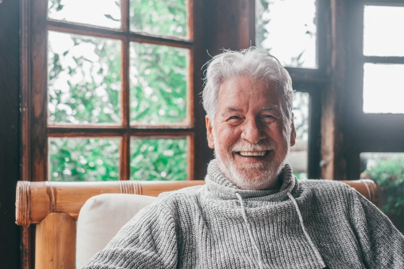 an older man smiling while relaxing at home